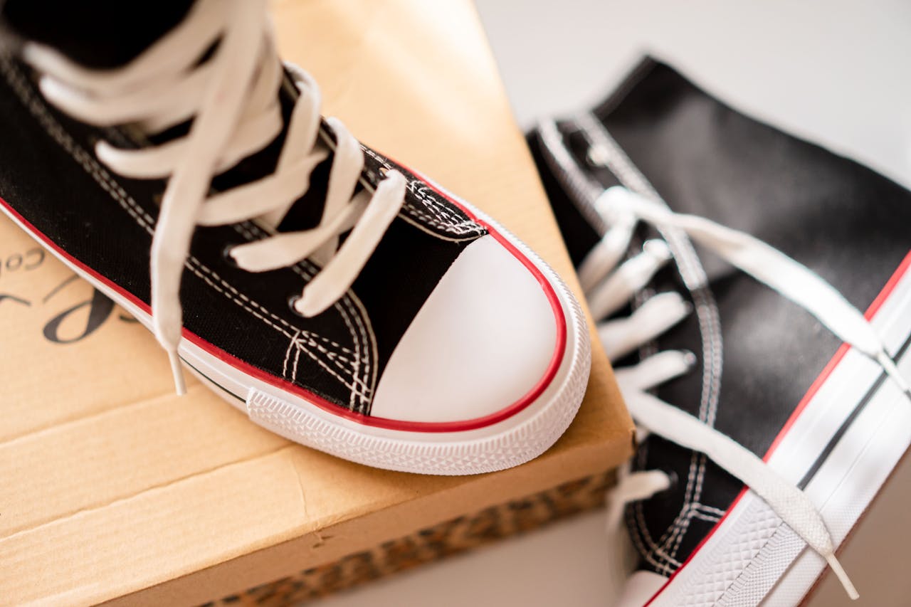Close-up of black and white sneakers with red trim on a cardboard box.