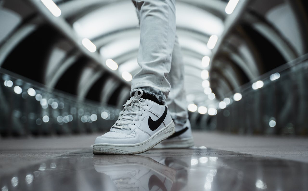Close-up of white sneakers with a modern urban backdrop, highlighting style and nighttime city vibes.